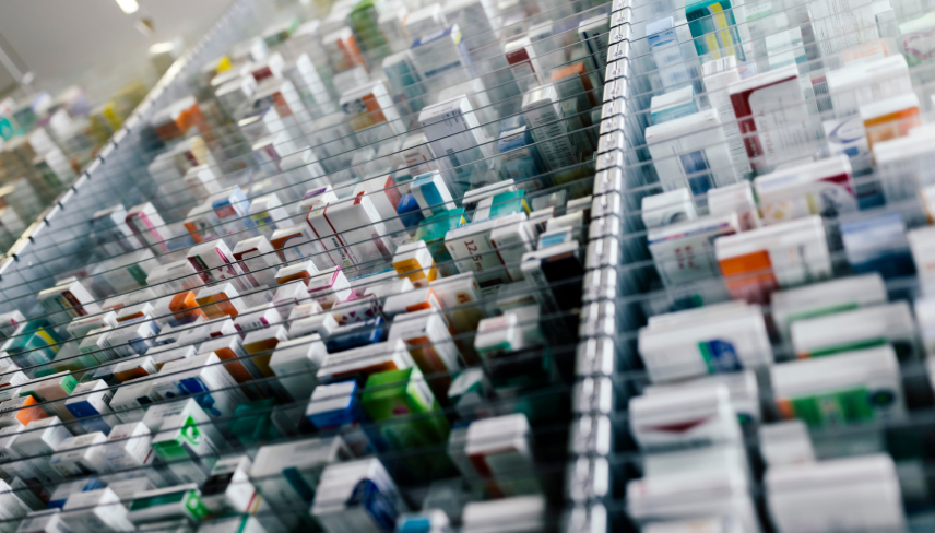 Rows of labeled prescription medication boxes organized neatly in a modern pharmacy storage system